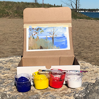 En Plein Air Painting of a tree taped to a box with jars of blue, yellow, red and white paint